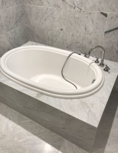 white bathtub with grey tile