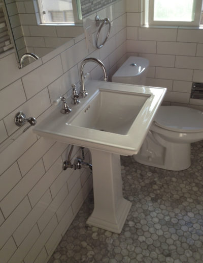 pedestal sink in white tile bathroom